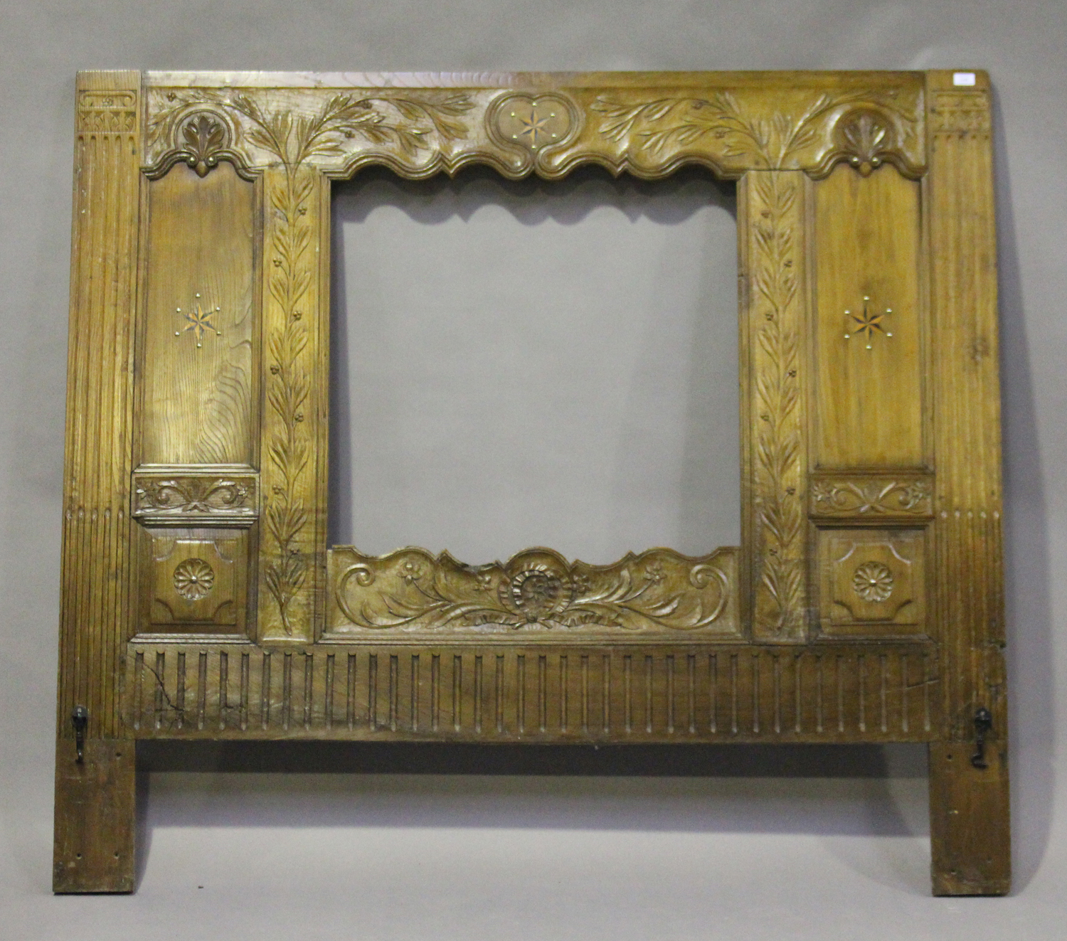 A 19th century French walnut headboard with central aperture, carved with overall leaf decoration