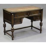 A George V oak kneehole writing desk, the top inset with tooled leather, on turned and baluster