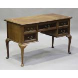 An early 20th century walnut kneehole writing table, the moulded top above five drawers, raised on