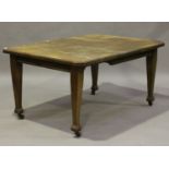 An Edwardian oak extending dining table with single extra leaf, raised on square tapering block