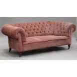 A late Victorian buttoned back Chesterfield settee, upholstered in pink velour, on turned legs,