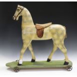 An early 20th century carved and painted wooden primitive push-along model of a horse, the plank