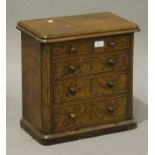 A Victorian burr walnut diminutive table-top chest of two short and three long drawers, on a