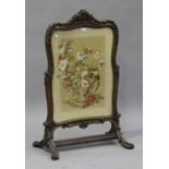 A Victorian carved walnut framed firescreen, inset with a needlework panel, on scroll feet, height