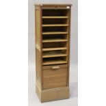 A mid-20th century oak tambour-fronted filing cabinet with sliding shelves, raised on a plinth base,