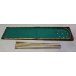 A late Victorian mahogany folding table-top bagatelle board, together with five cues.Buyer’s Premium