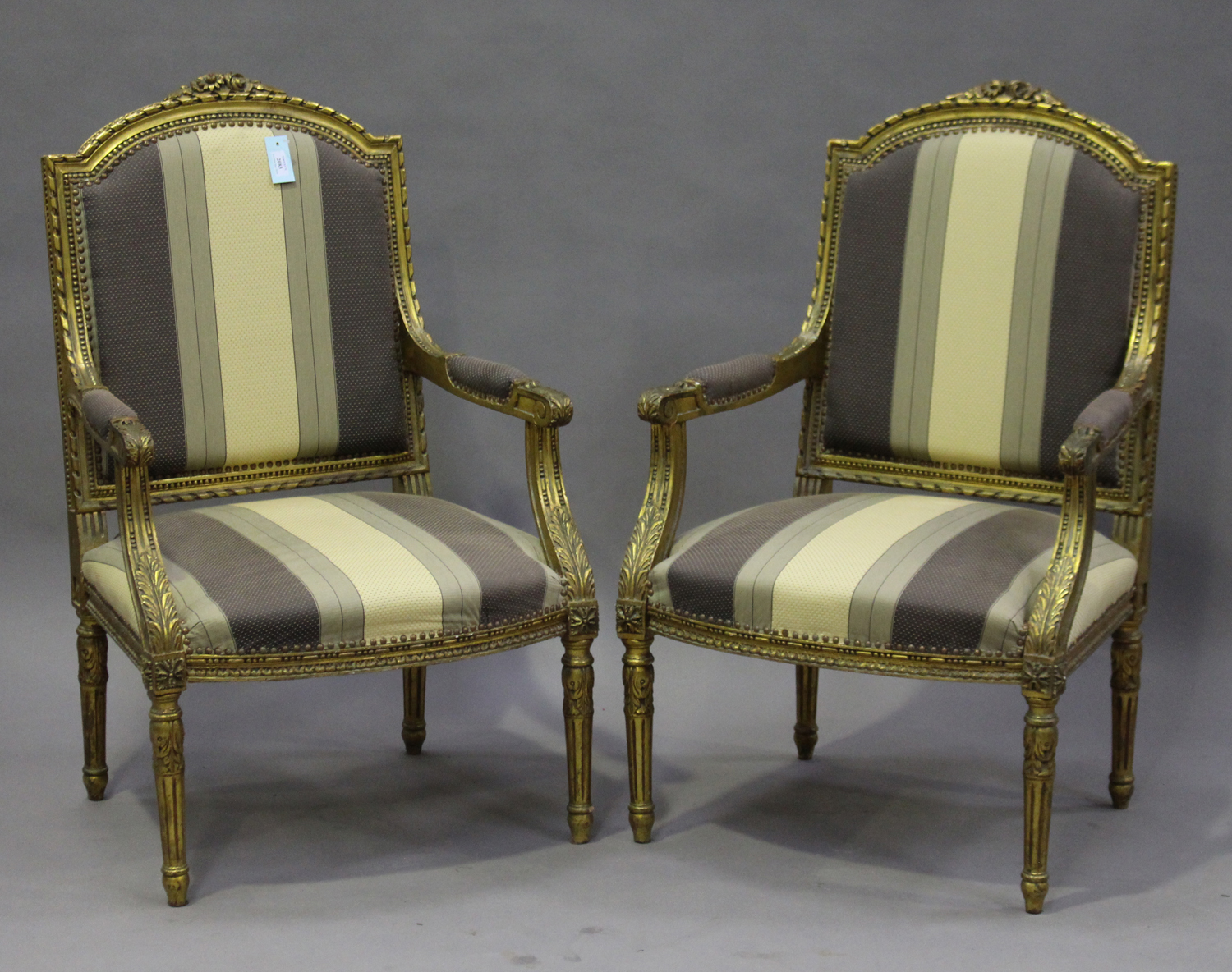 A pair of early/mid-20th century Louis XVI style giltwood fauteuil armchairs, the overstuffed