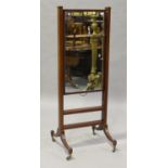 A Regency mahogany cheval mirror with rising ratchet mechanism, on sabre legs and brass castors,