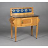 An Edwardian Arts and Crafts style oak washstand, the back inset with blue glazed tiles above a