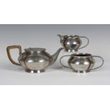 A late Victorian Arts and Crafts 'English Pewter' three-piece tea set, each squat circular body with
