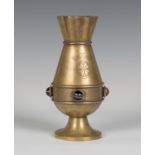 A late Victorian Gothic Revival brass vase by Jones & Willis, the shaped rim above a flared body and