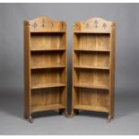 A pair of Edwardian Arts and Crafts oak five-tier open bookcases, probably by Liberty & Co, the
