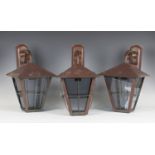 A set of three mid-20th century Arts and Crafts style patinated copper wall lanterns, the