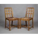 A pair of early 20th century oak lattice back dining chairs, probably by Heals, raised on