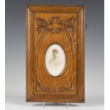An Edwardian Arts and Crafts oak photograph frame, the oval aperture within a surround of two