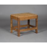 An early/mid-20th century Cotswold School oak framed stool, the woven rattan seat raised on
