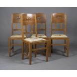 A set of four Edwardian Arts and Crafts oak framed and ash backed dining chairs, designed by W.J.