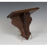 A late Victorian Aesthetic Movement oak wall bracket, the pierced support and shaped backplate