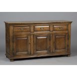 A late 20th century Carolean style oak dresser base, fitted with three drawers above panelled doors,