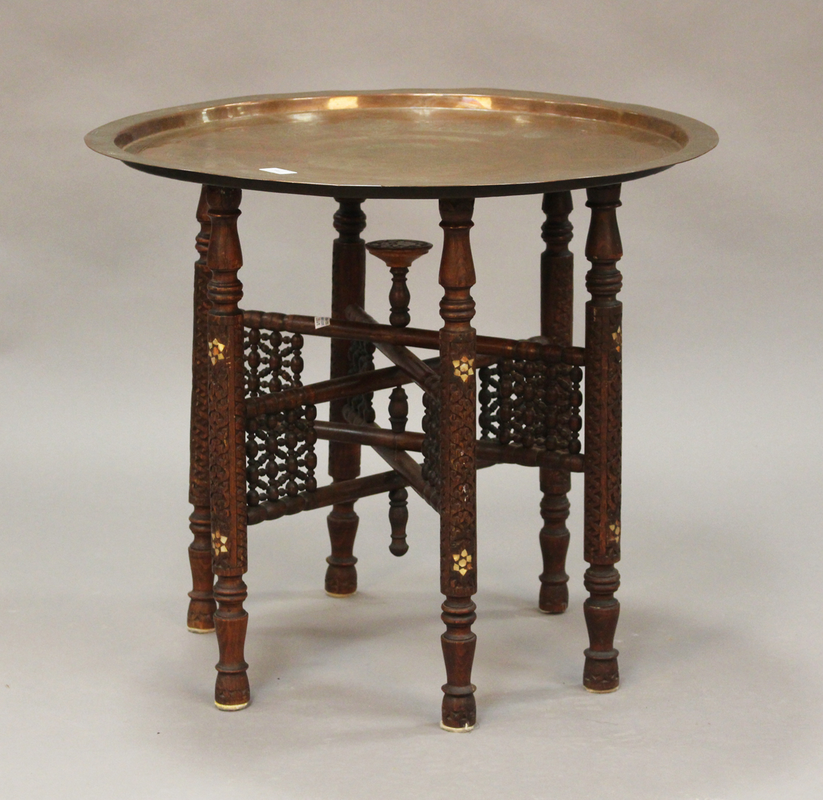 A late 19th/early 20th century Middle Eastern Islamic tray-top table, the circular copper tray