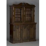 A late Victorian mahogany glazed bookcase cabinet, the swan neck pediment above two glazed doors and