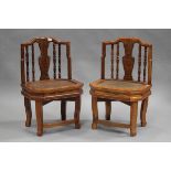 A pair of 20th century Chinese softwood low side chairs with carved splat backs and inset rattan