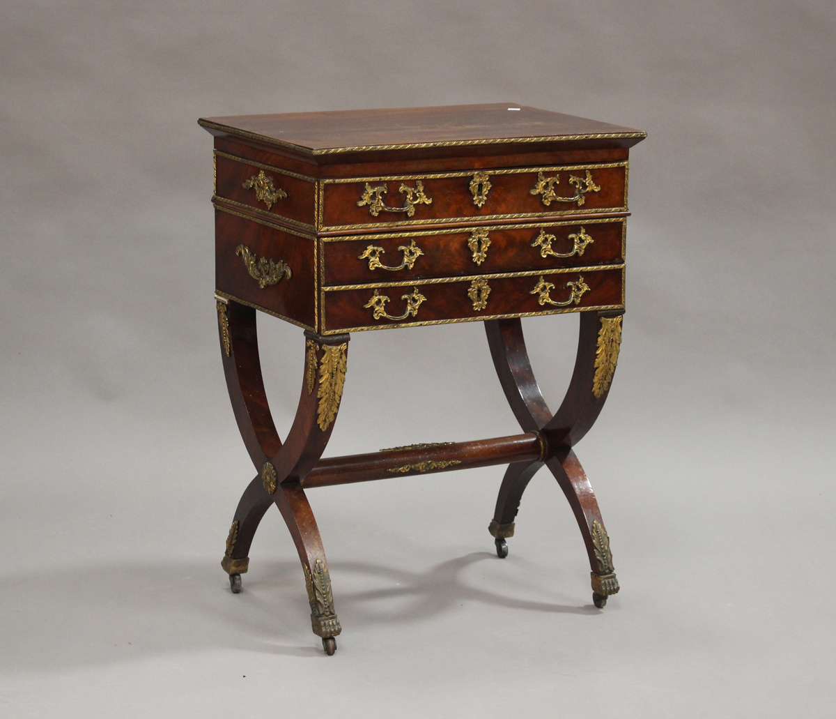 A 19th century figured mahogany and gilt metal mounted sewing table, the hinged lid enclosing a