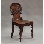 An early Victorian mahogany hall chair, the back carved as a shell above a solid seat, on turned