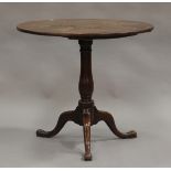 A late George III provincial oak circular tip-top wine table, raised on a turned baluster stem and