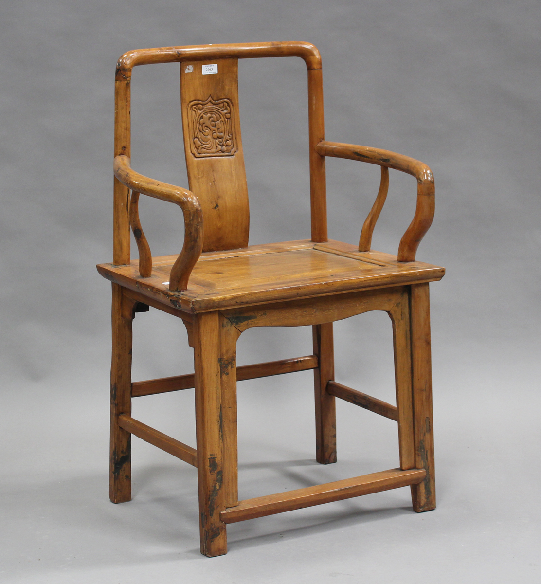 A 20th century Chinese softwood elbow chair with a carved splat back and panelled seat, on block