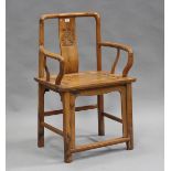 A 20th century Chinese softwood elbow chair with a carved splat back and panelled seat, on block