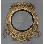 A Regency giltwood and gesso convex girandole wall mirror, the floral scroll surmount above a