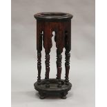 An early 20th century oak circular stick stand raised on turned supports, the base inset with a