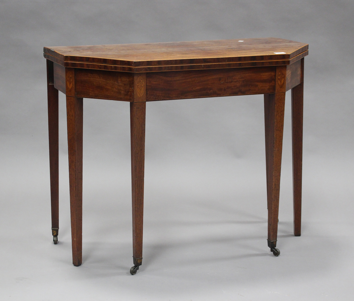 A George III mahogany fold-over tea table, the canted top with boxwood stringing, the frieze with