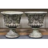 A pair of late 20th century cast composition stone garden urns, decorated in relief with masks and