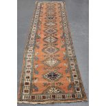 A Turkish runner, mid-20th century, the pink field with a column of hooked and linked medallions,