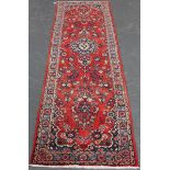 A Hamadan runner, North-west Persia, mid-20th century, the red field with a shaped medallion,