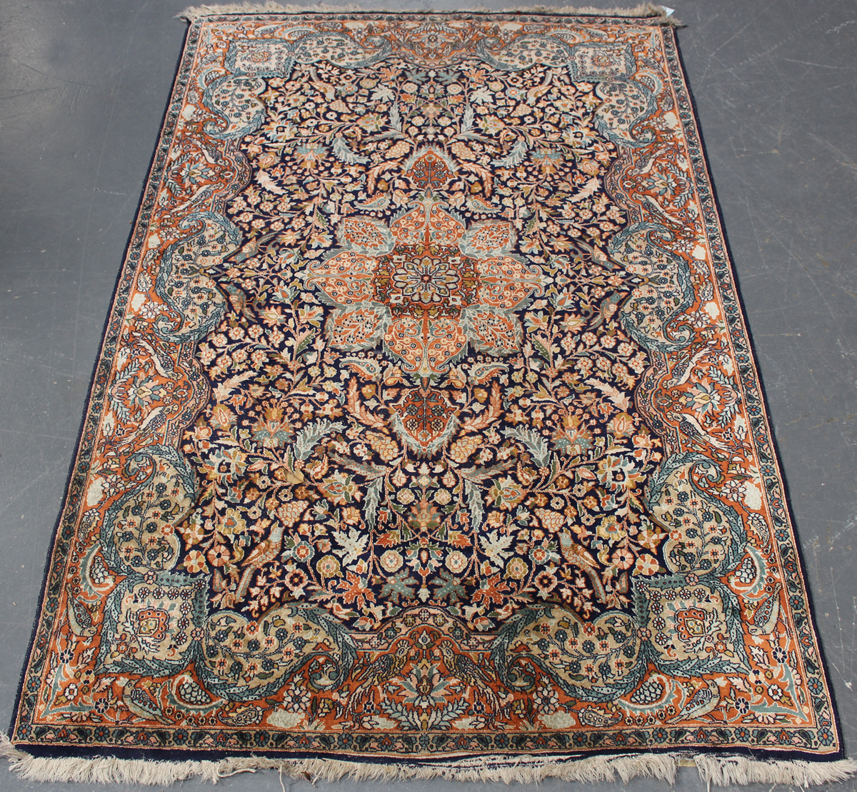 A Turkish part silk rug, late 20th century, the midnight blue field with a flowerhead medallion,