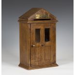 A modern oak letter box, modelled in the form of a porchway, the arched top above a glazed door,