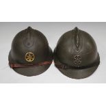 Two early 20th century French Adrian pattern military helmets, both with applied badges, leather