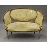 An early 20th century Louis XVI style giltwood showframe salon settee, upholstered in patterned
