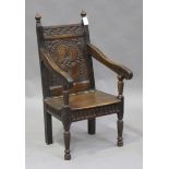 A 17th century and later oak Wainscot armchair, the carved panel back above a solid seat, flanked by
