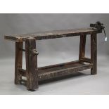 An early 20th century stained wooden work bench, fitted with cast iron vice and wooden clamp, height