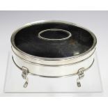 A George V silver oval jewellery box with inset tortoiseshell panelled hinged lid, raised on foliate