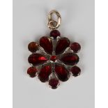 A gold and foil backed flat cut garnet pendant, mounted with six pear shaped garnets and seven