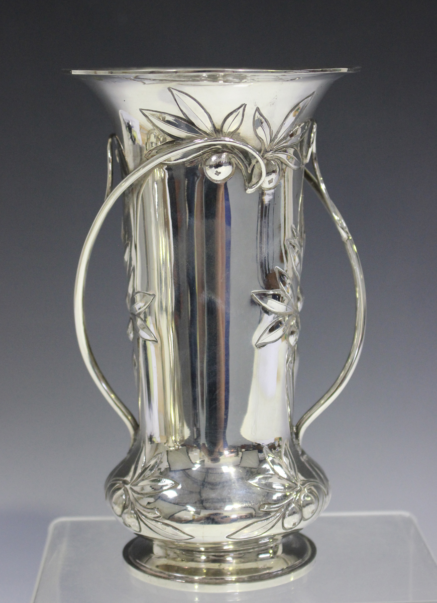 An Edwardian Arts and Crafts style silver trumpet vase, decorated in relief with leaves and berries,