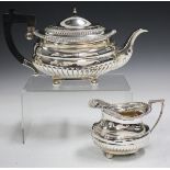 A George V silver teapot and matching milk jug, each of half-reeded oval cushion form with gadrooned