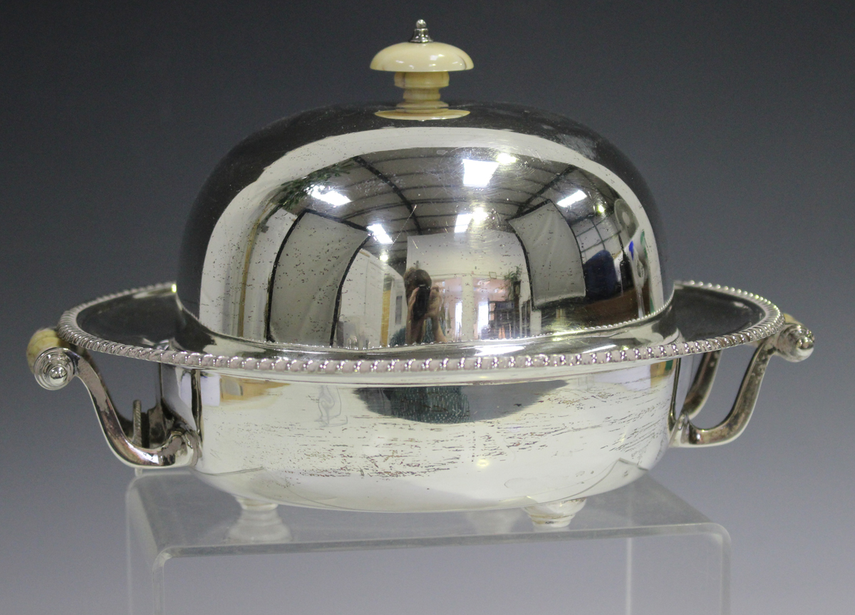 A George V silver muffin dish and cover with warmer base, fitted with turned ivory finial and