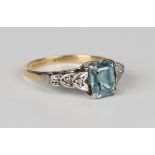 A gold and platinum ring, claw set with a cut cornered rectangular blue zircon between rose cut