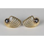 A pair of gold and sapphire single stone earstuds, each in a scrolled wirework design, claw set with